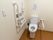広い個室トイレに温水洗浄便座がある。壁には大きな操作ボタンやひも付きの緊急呼び出しボタンがあり、操作性が配慮されている。