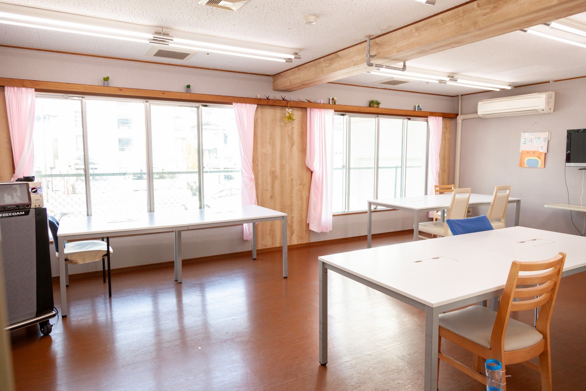 大きな窓が付いた居室には介護用ベッドやエアコン、テレビやテーブルセットが付いている。