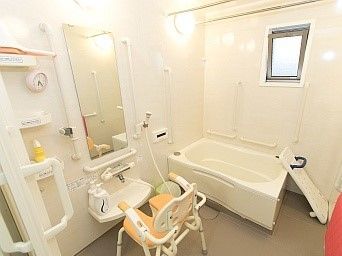 一人用の浴槽が設置された浴室。シャワーや鏡、シャワーチェアもあり、手すりが壁についている。