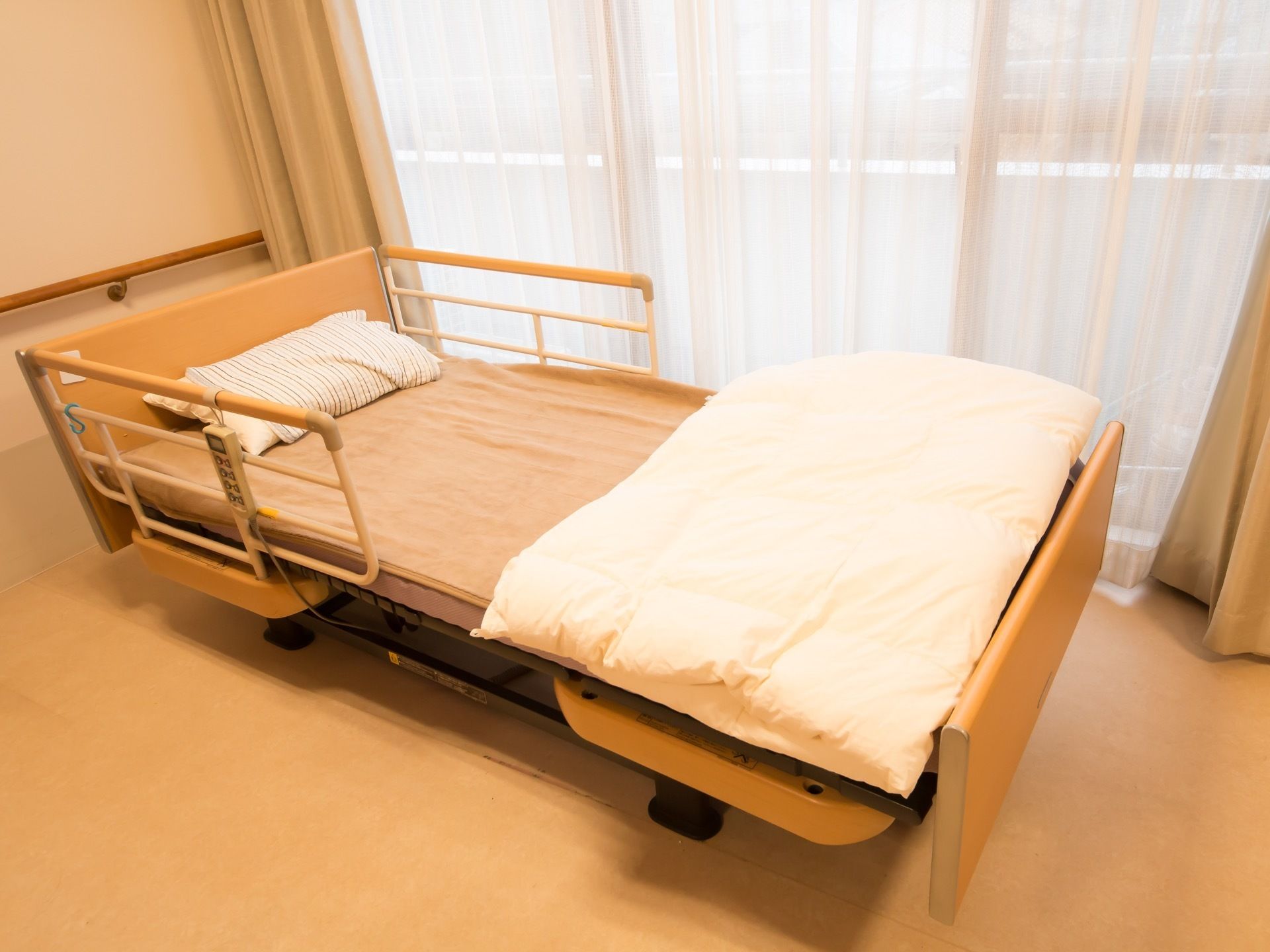 電動式の介護用ベッドが置かれている。すぐにご利用いただけるように枕やシーツ、上掛けの布団が設置されている。