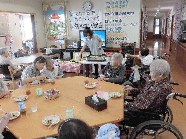 スタッフが造り軽食をテーブルを囲んで食べている入居者。車いすの入居者もできることは自分でしている。