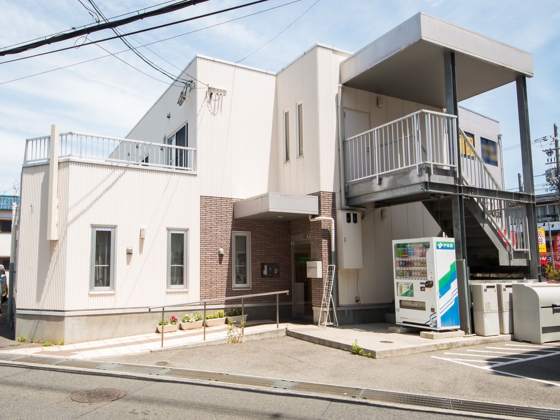 施設建物の外観。敷地内は完全に舗装されている。正面玄関前にはスロープが設けてあり、その奥側には外階段が設置されている。