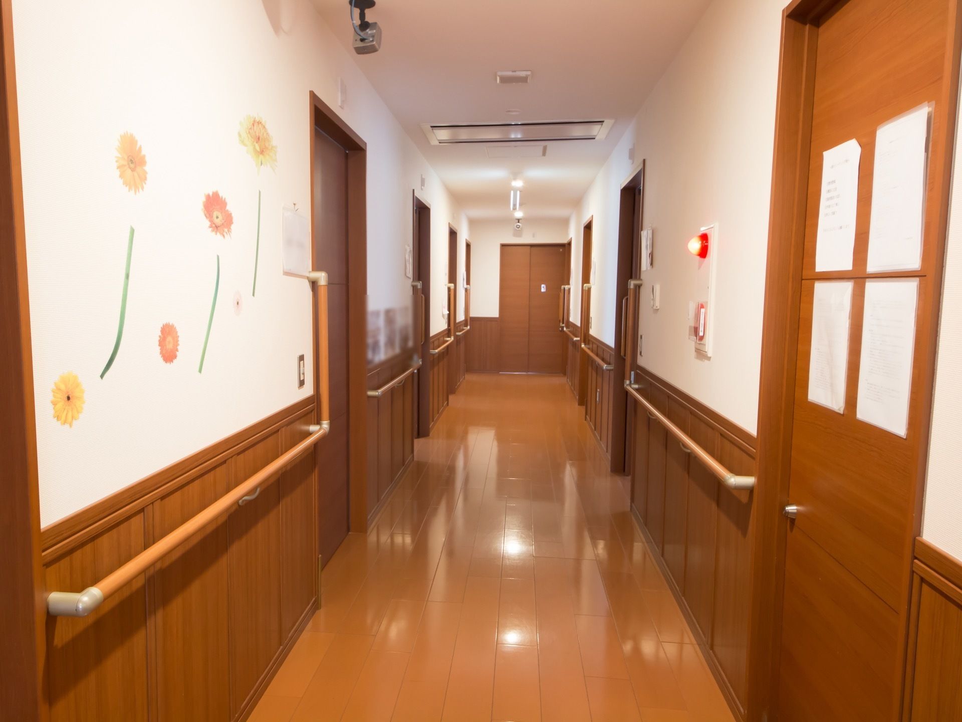明るい茶色の通路で、その両側には同系色のドアが並んでいる。白色の壁には花のインテリアシートが貼られている。