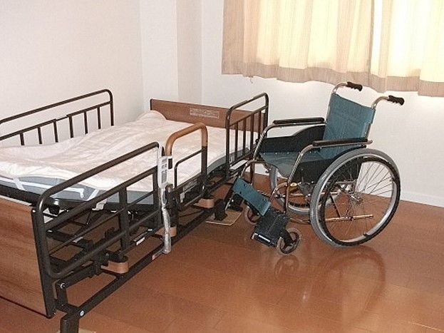 柵が付けられた介護用ベッドの横に車いすが置かれている。