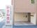 大きな赤い文字で施設名称が表示された看板が道路沿いに立っている。玄関扉の横にも横書きの看板が掲示されている。