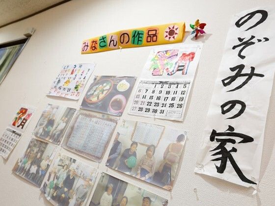 ホーム名が書かれた習字や塗り絵付きのカレンダー、イベント写真などが貼られている壁。