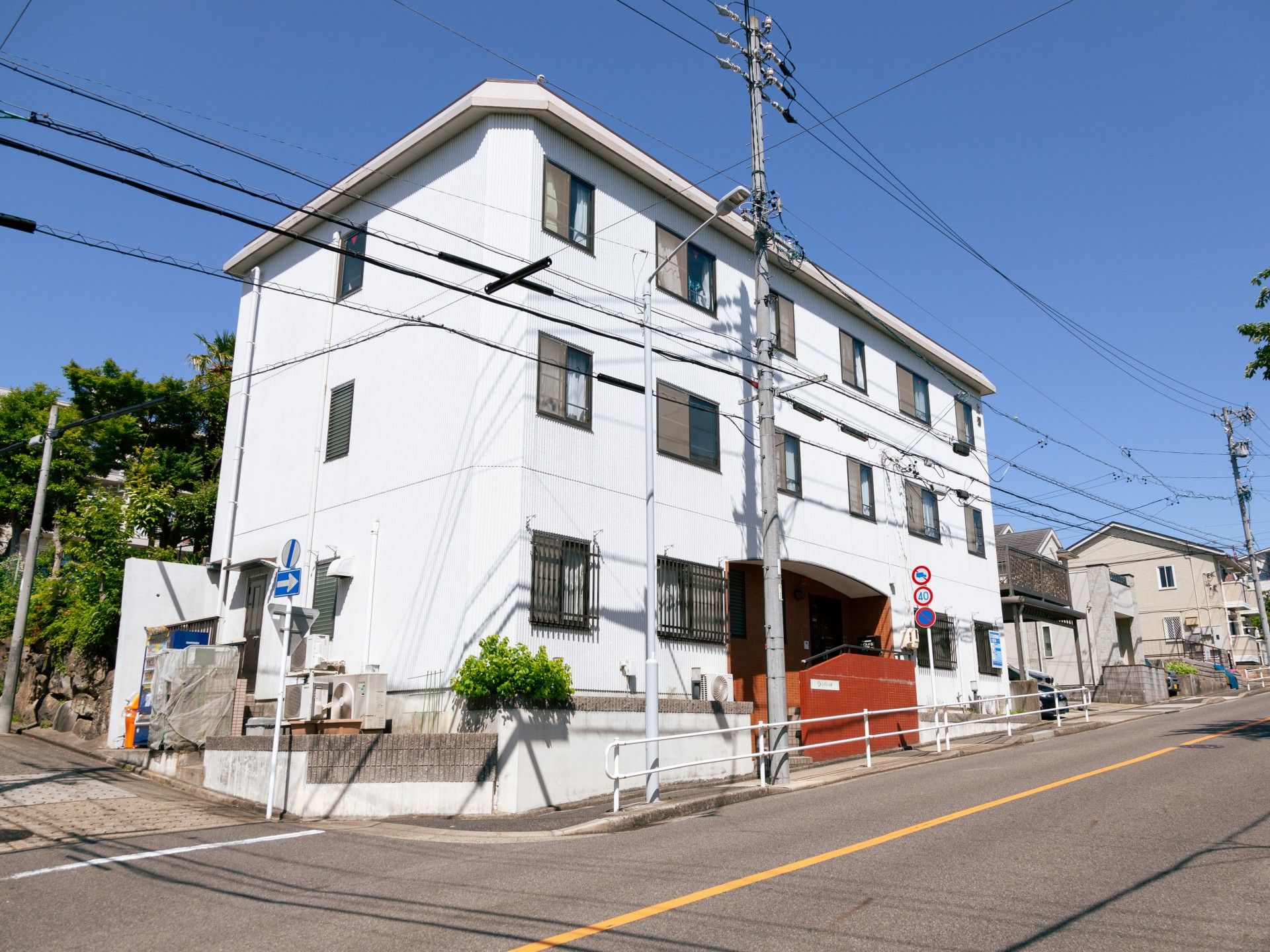 グレーの３階建ての建物部分にはレンガ調の門があり、周囲にもたくさんの建物が建っている。