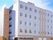 ５階建ての大きな建物は白でまとめられていてすっきりとした印象。左側に看板がある。