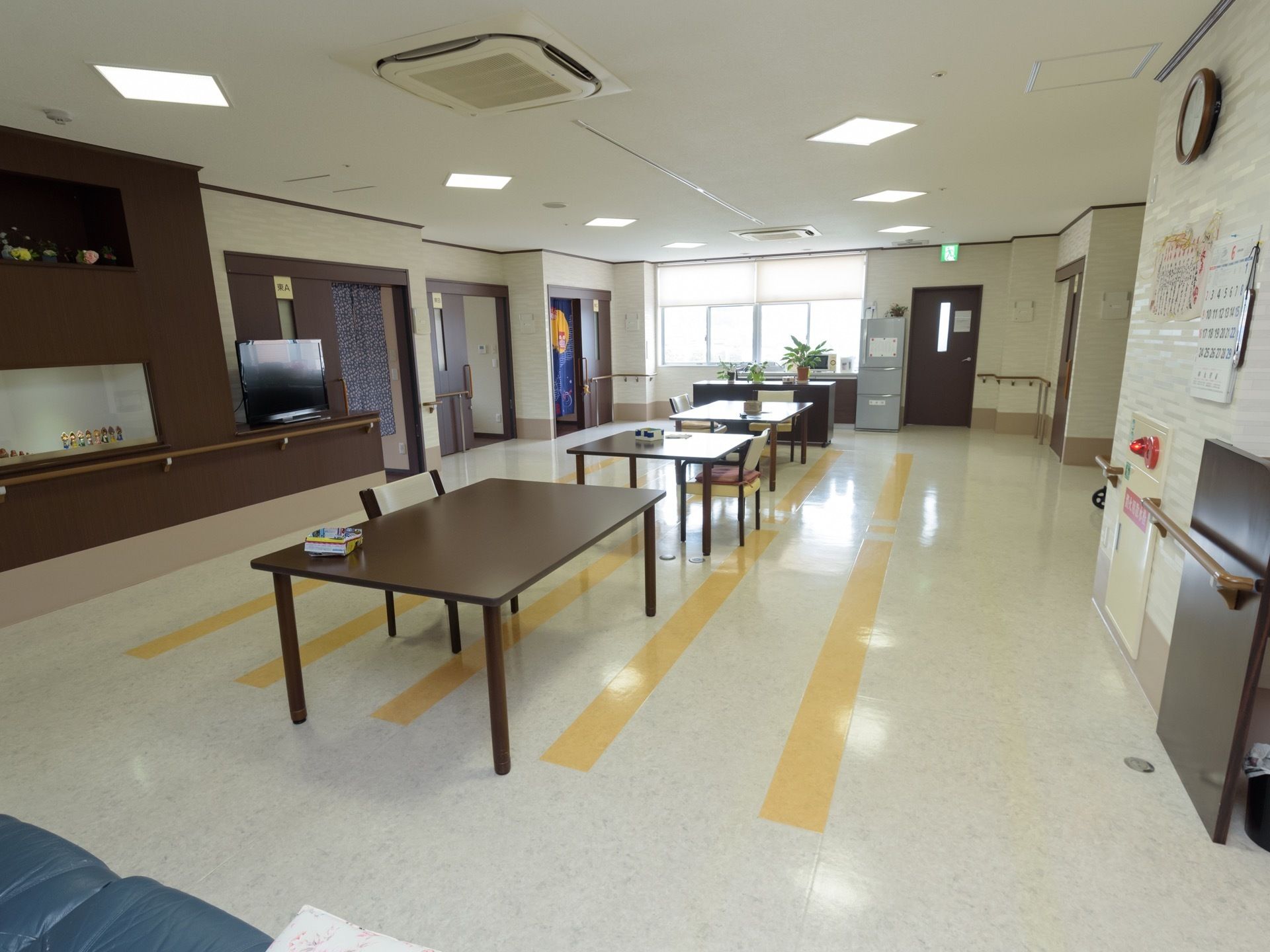 中央に複数のテーブル席が用意されている。窓側にシンクがあり、電子レンジが用意されている。右側には冷蔵庫がある。