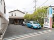 建物と車道までは距離があり、車が複数台停められるようになっている。隣の建物とはフェンスで仕切られている。