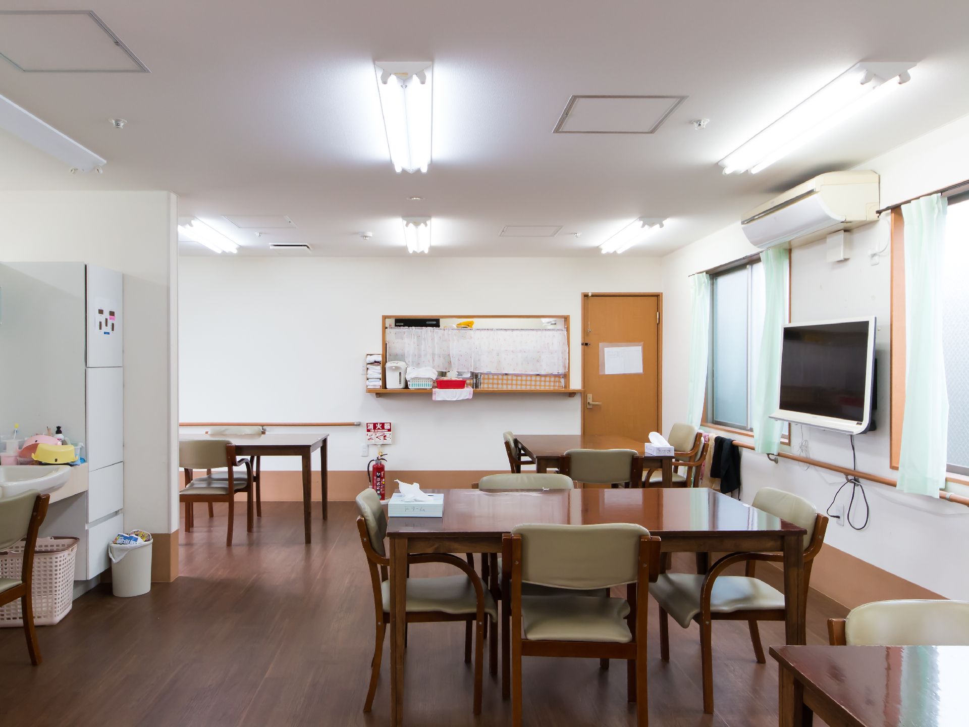 正面にカウンターと茶色いドアがあり、右の壁面にテレビがかけられた食堂