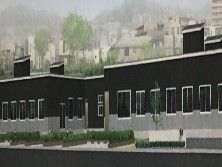 黒とグレーの平屋建ての建物。周辺には住宅や緑があり、建物の周りには緑も植えられている。