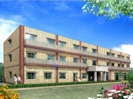各フロアにはベランダが設置され、建物周辺には緑が植えられたベージュの建物。どっしりとした3階建て。