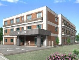 3階建ての建物。ブラウンと白でまとめられ、温かい雰囲気の外観。ホーム周辺には緑もたくさん植えられている。