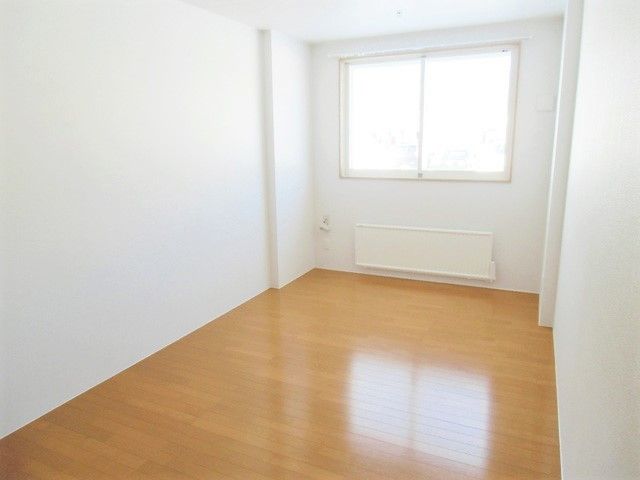 フローリングの居室。家具はなくパネルヒーターが窓の下にある。