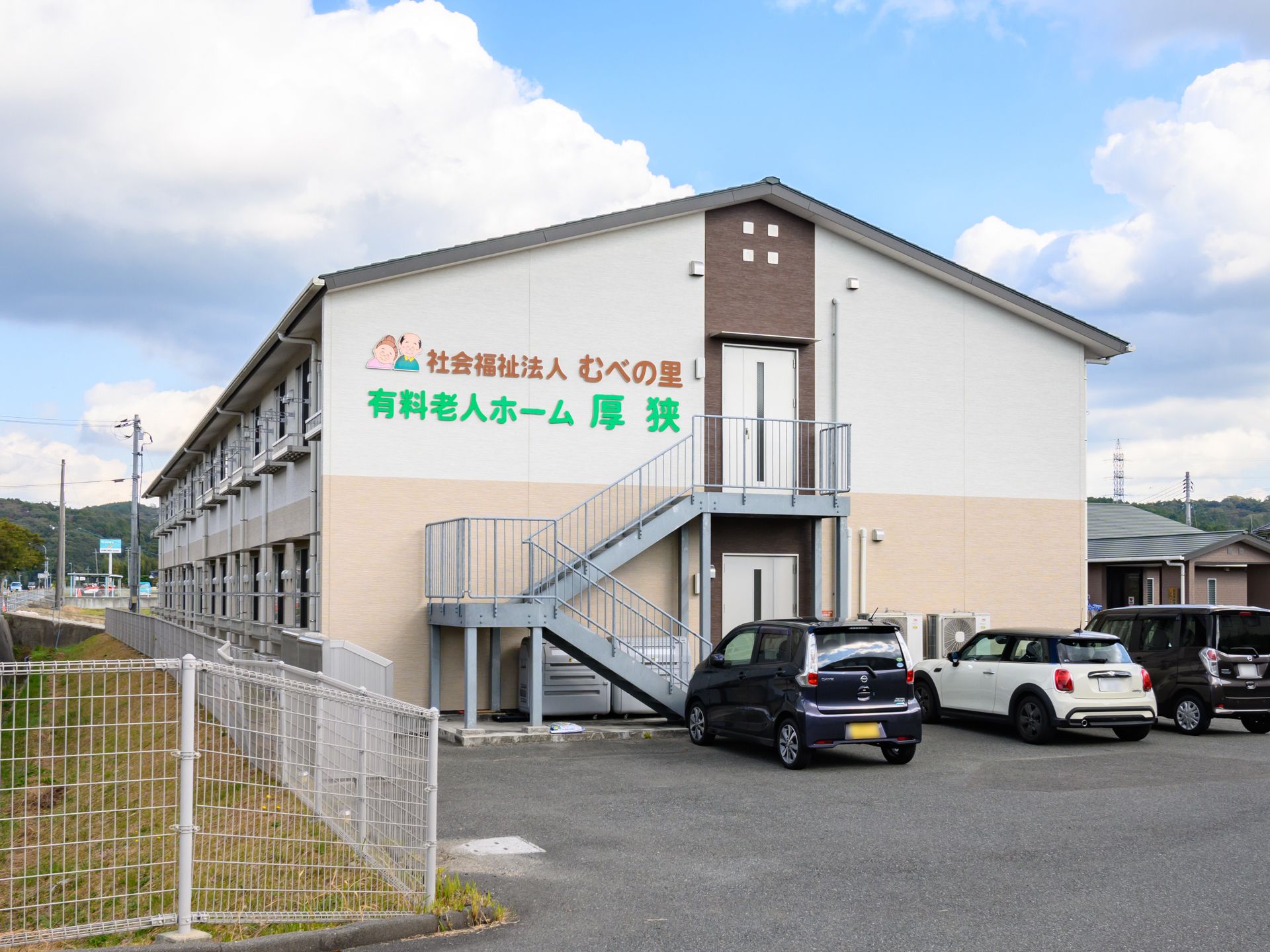 木陰にいる車椅子に乗った高齢男性と付き添う女性ヘルパー