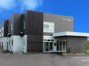 モノトーンの落ち着いた外観。外壁にはホーム名が書かれ、車寄せもついている。