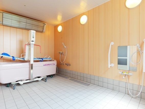 木目調の壁が設置された浴室には機械浴とシャワーがある。