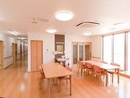 木製のダイニングテーブルが複数置かれ、ぬくもりが感じられる館内。左には廊下がある。