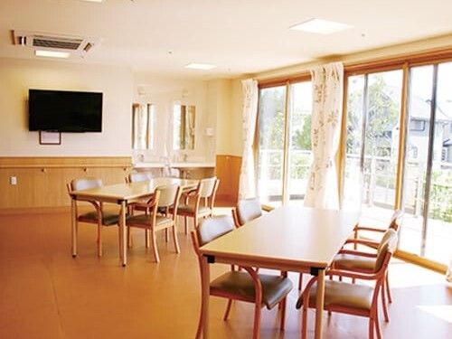 大きな壁掛けテレビが設置された食堂には木製のテーブルが複数置かれ、外にはテラスがある。