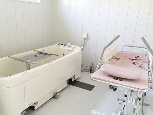ストレッチャータイプのリフトと浴槽型の機械が置かれている浴室。寝たまま入浴可能な寝台浴。