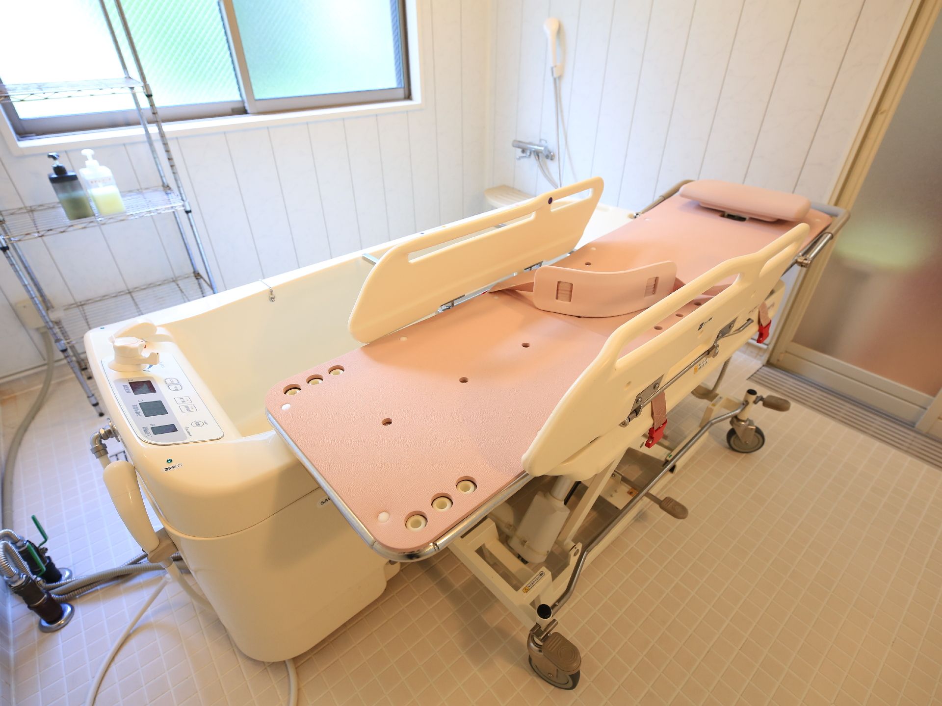 寝たまま入浴できる浴槽と、専用のピンクのストレッチャーが置かれている浴室