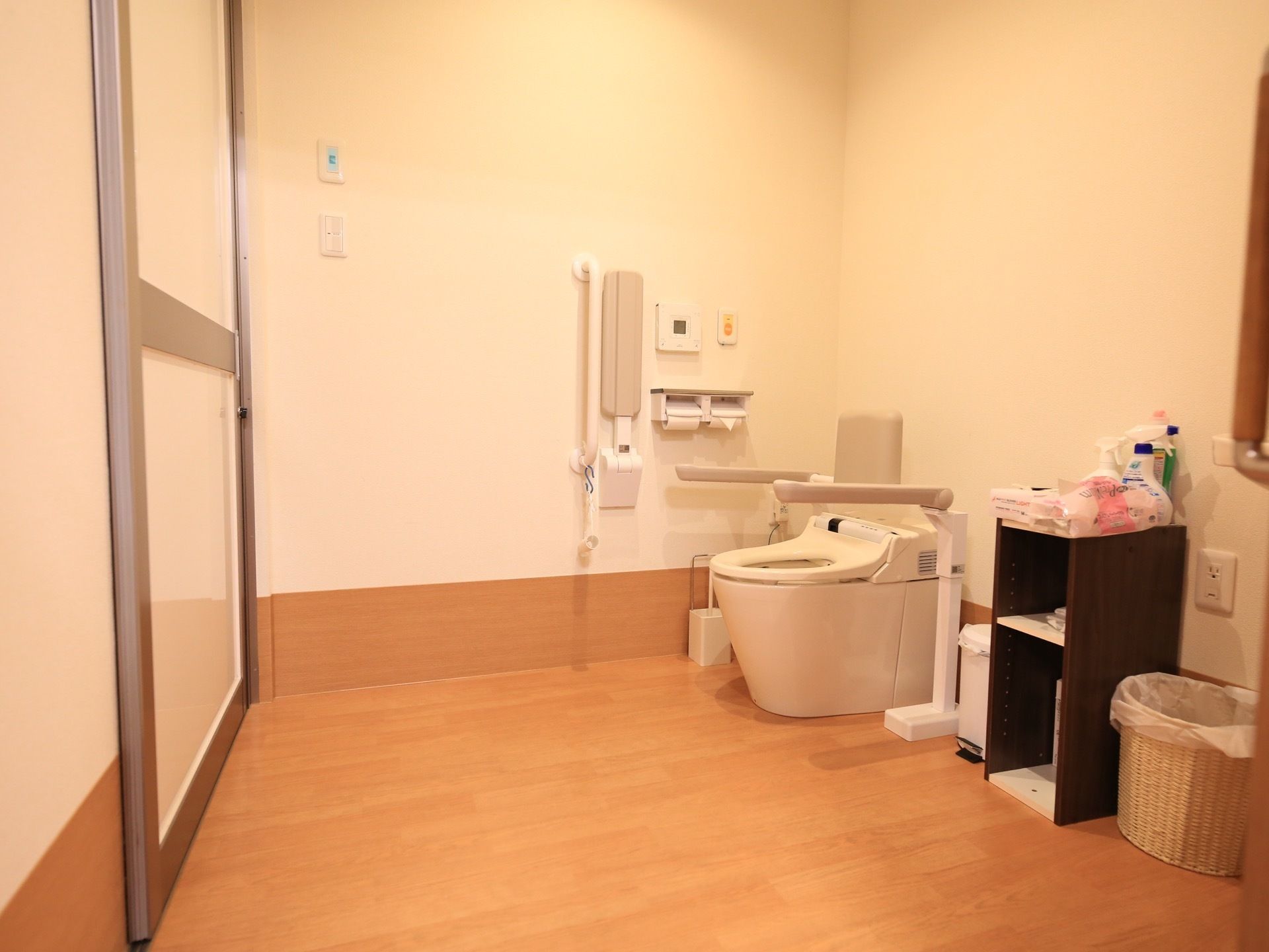 広々としたトイレである。温水洗浄便座のトイレが設置されており、壁には手すり、ペーパーホルダーが取り付けられている。