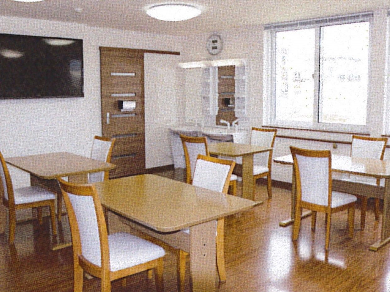 木製テーブルは二人掛けで4つ並んでいる。壁掛けテレビや洗面所もある。
