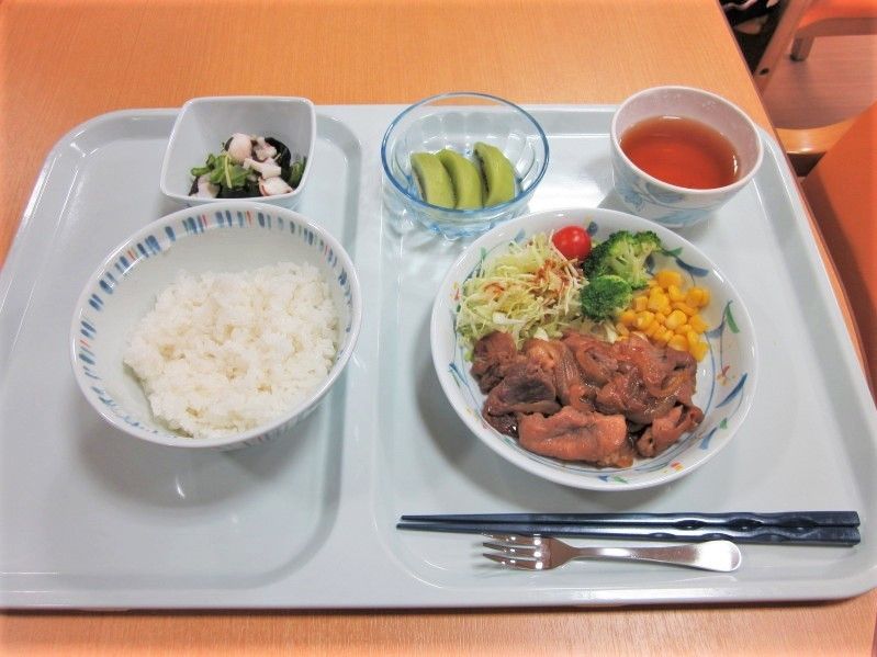肉料理をメインとした食事。野菜の和え物やご飯、フルーツが添えられている。