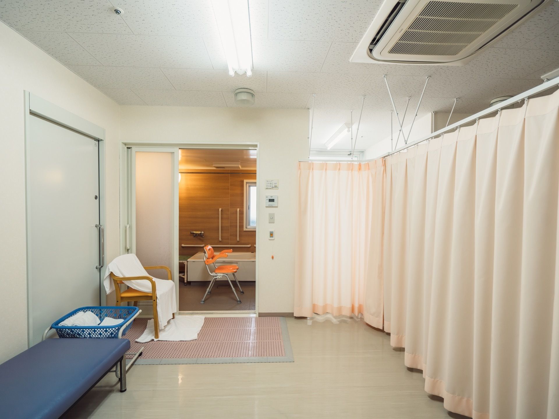 個室タイプの浴室と更衣室の間にあるドアは３段スライドになっている。その足元にはバスマットが敷いてある。