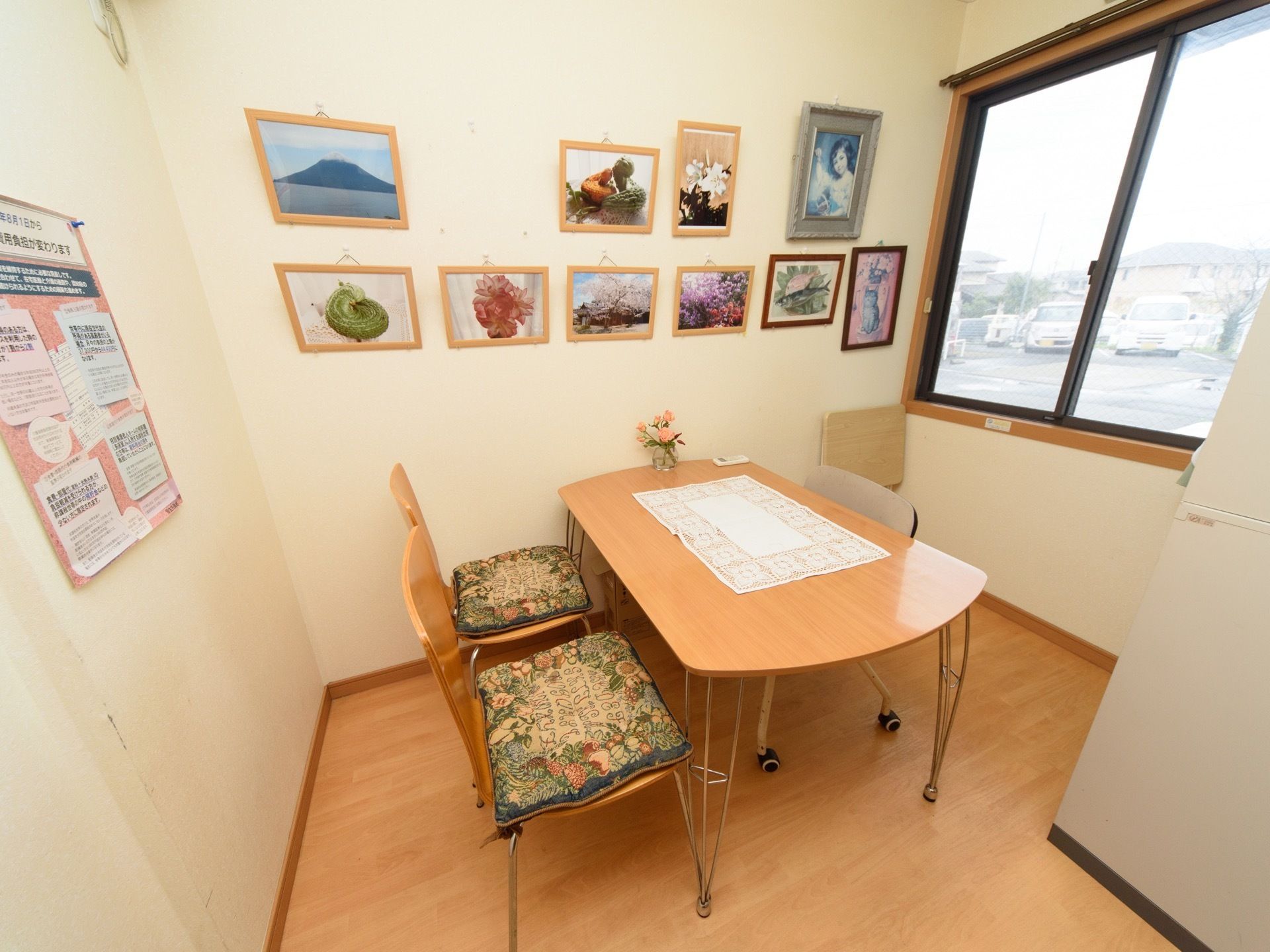 相談室の白い壁には、小さな額に入った絵画や写真が所狭しと飾られている。部屋の中央には、4人掛けのテーブルを配置している。