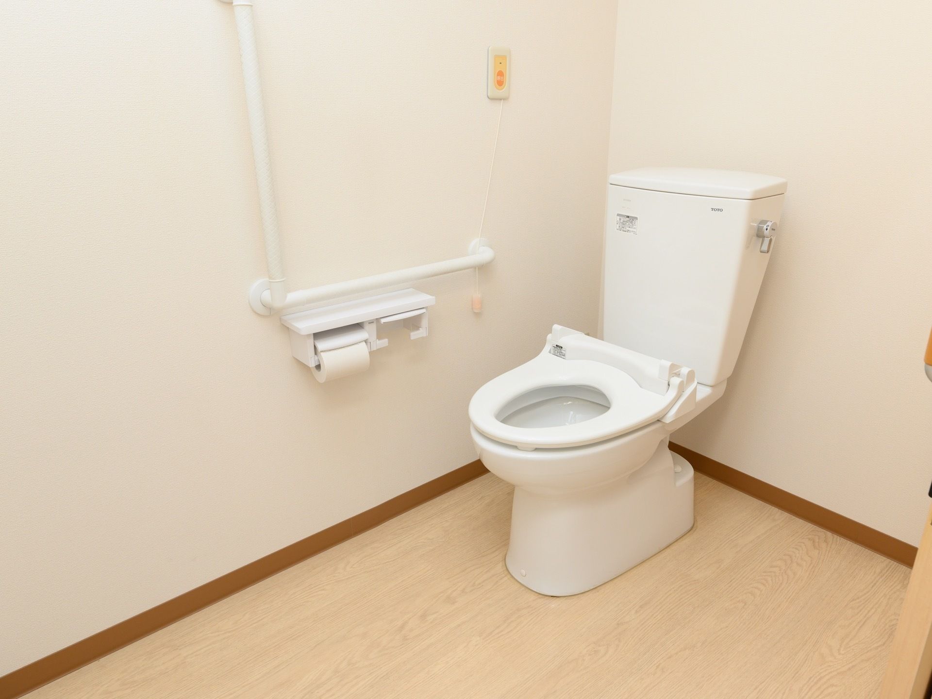 壁にＬ字型の手すりが設置されており、その下に２個並びのトイレットペーパーホルダーが取り付けられている。