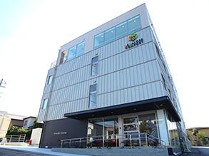 背の高い建物の玄関先には手すりが設置され、玄関には屋根が付いている。