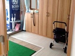 段差がなく、フロアの素材で館内の中と外の区切りを付けている。傘立てには数本傘があり、黒いシルバーカーも置かれている。