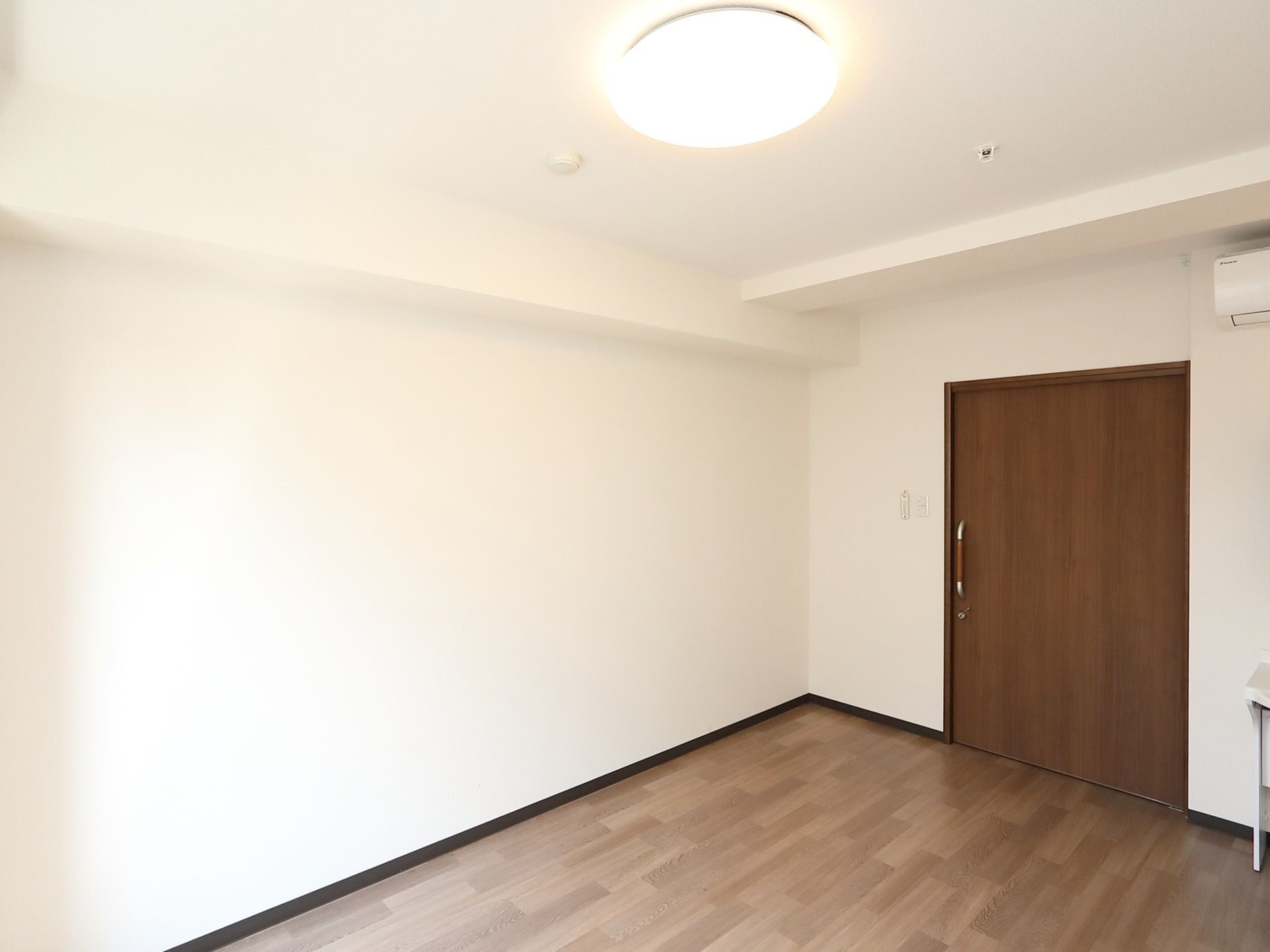 白壁の広々とした居室には、あらかじめ大きな照明器具と冷暖房が完備されている。床は車椅子でも移動しやすいフローリング仕様である。