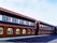 ブラウン系の2階建ての建物は横に長く、白線が引かれた駐車場があり、周りに建物はない。