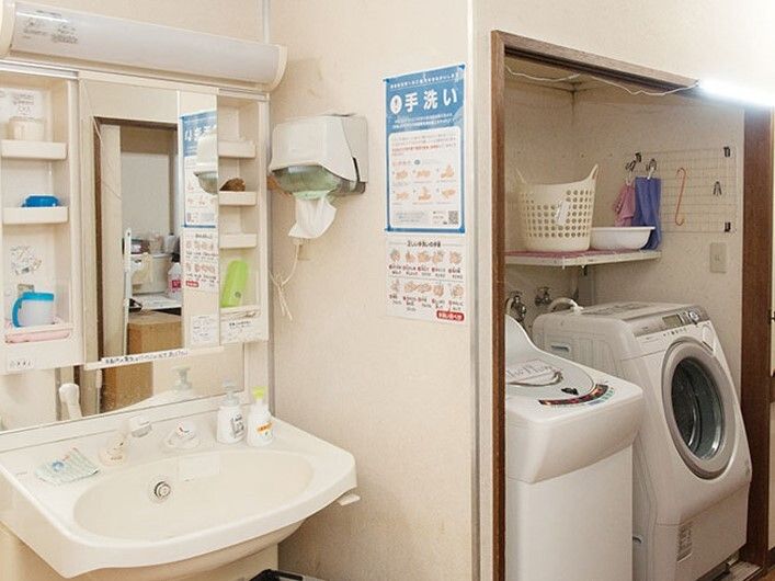 洗濯機が置かれているスペースの左側には収納や鏡などが付いた洗面所があり、それぞれ照明付き。