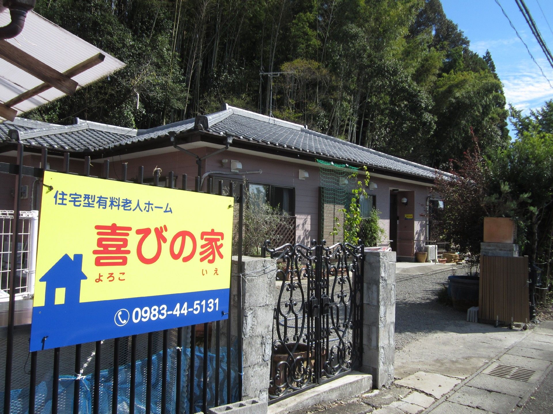 看板がかけられた門を入ると、平屋建てのホームがある。