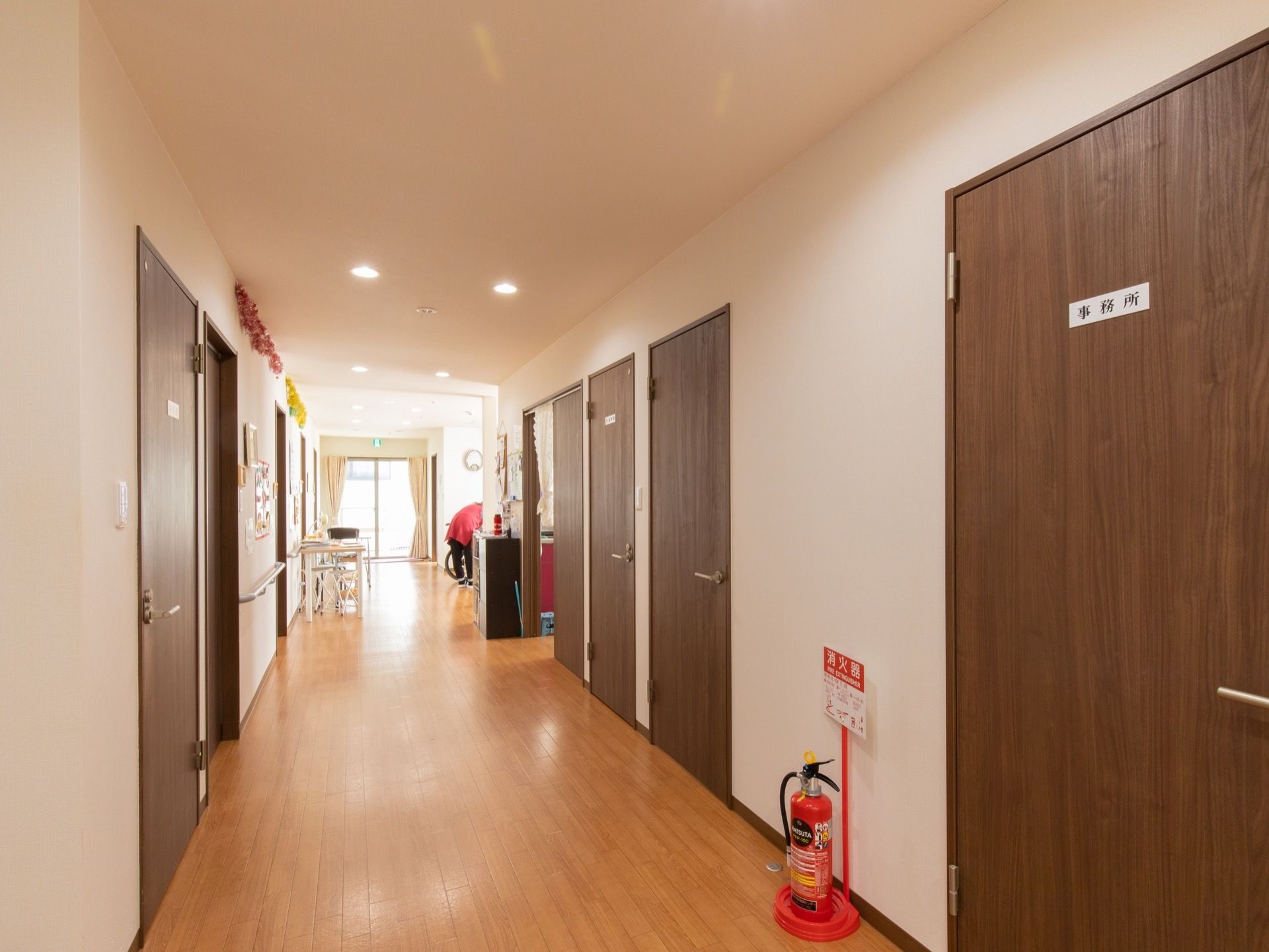 通路幅が広い廊下になっている。通路には消火器が設置されている。各部屋の扉はシックなブラウンカラーになっている。
