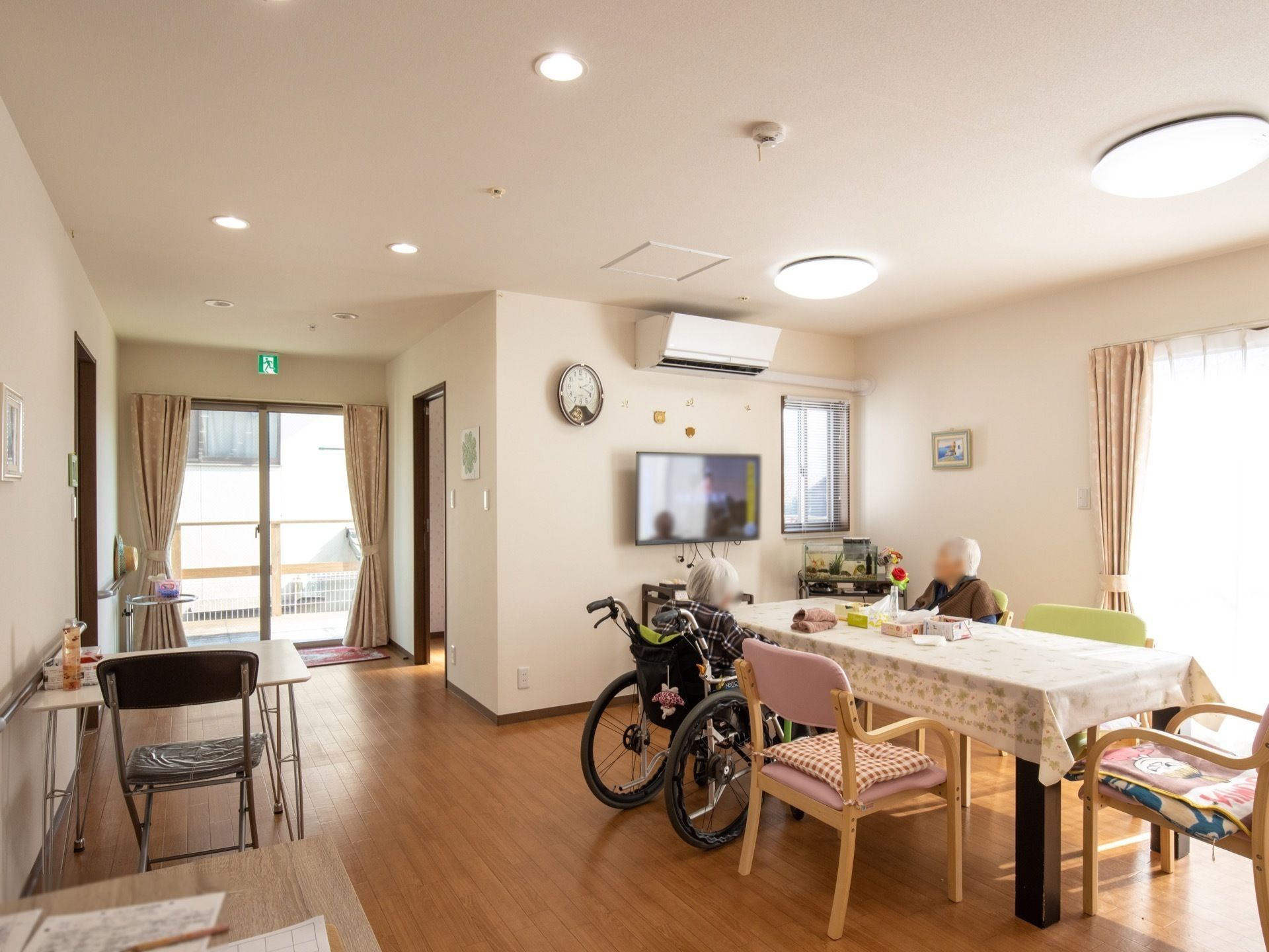 クロスのかかったテーブルが置かれ、入居者様がテレビを見ている食堂