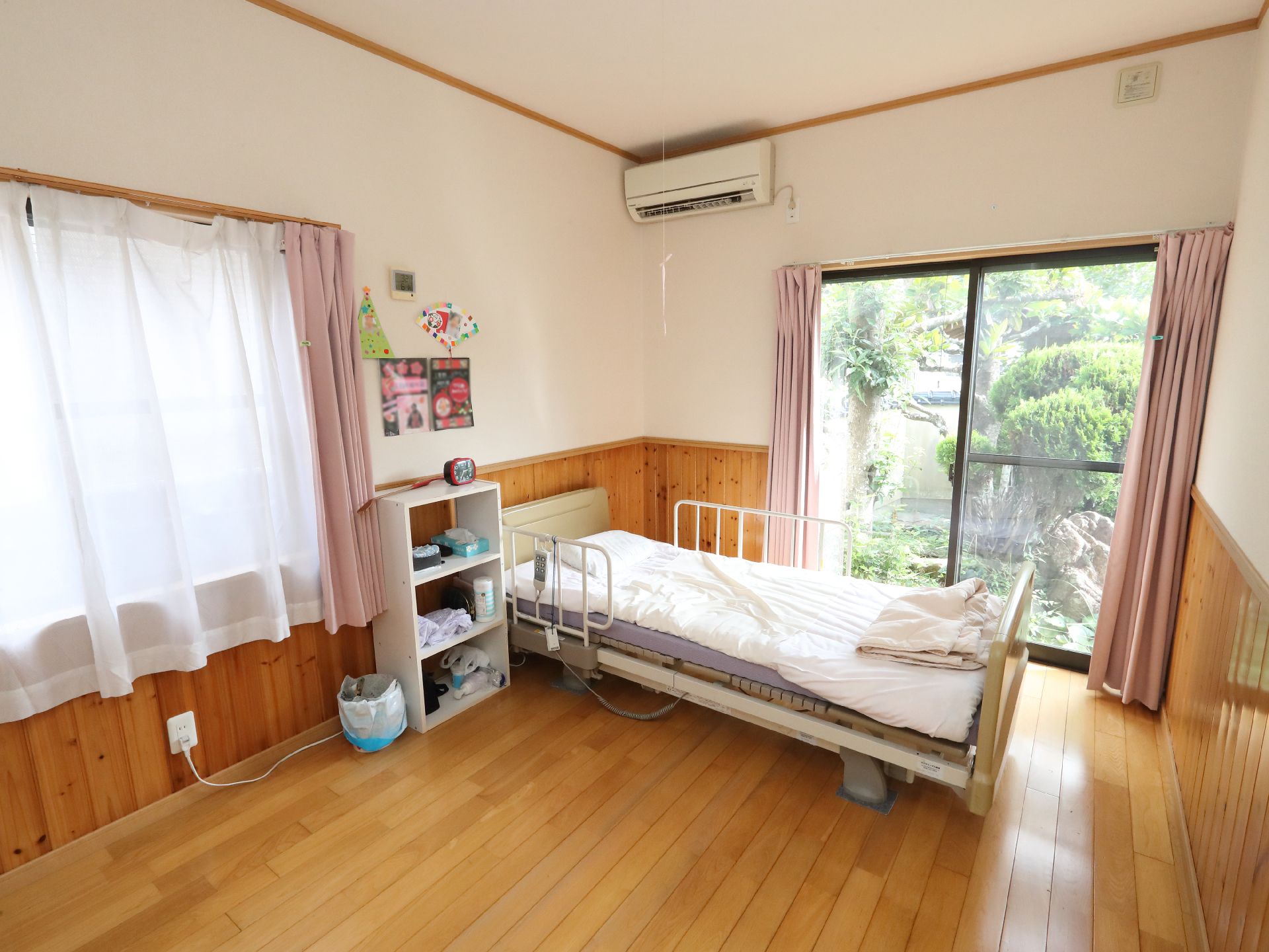 高齢者の方にタオルをかけてマッサージしているスタッフと振り返りながら会話する女性の様子