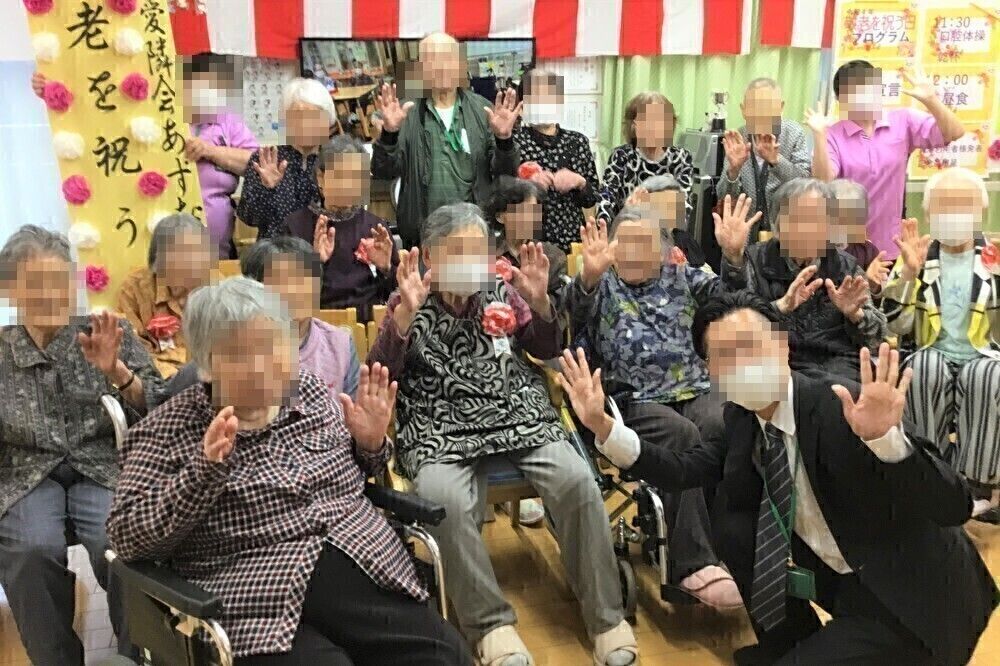 紙を使ったレクリエーションをする高齢女性と女性スタッフ