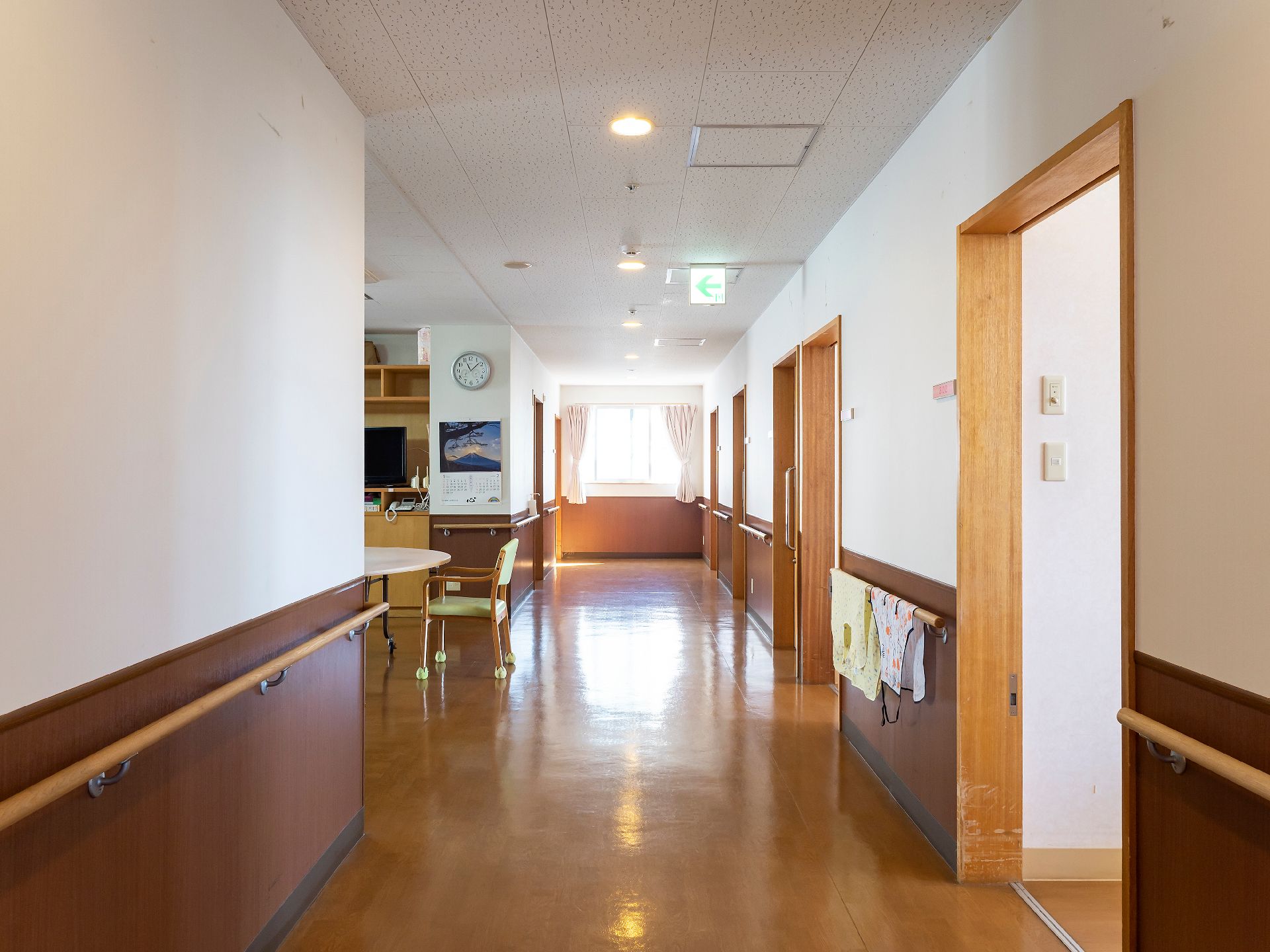 芝生広場で笑顔で語り合う高齢夫婦と若い女性。座って話をしている。