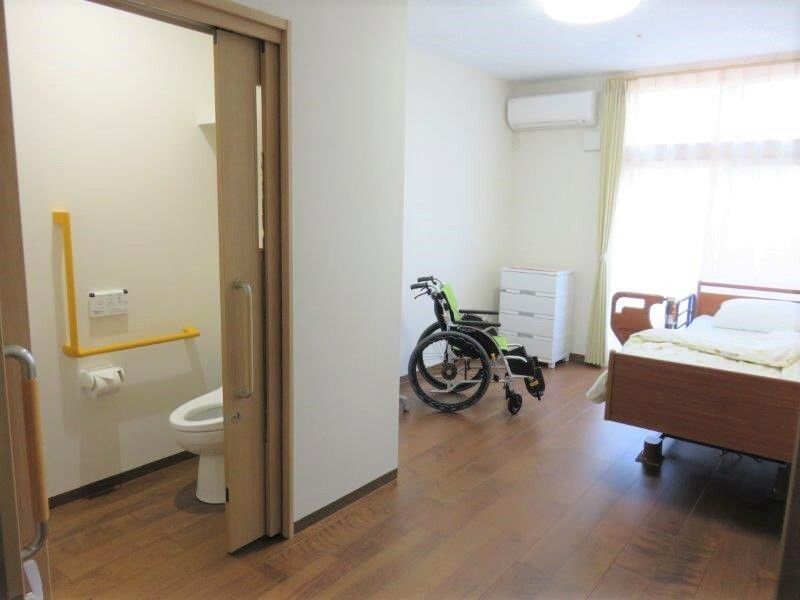 トイレやエアコンがついた小さなワンルームタイプの部屋。車いすが置かれている様子