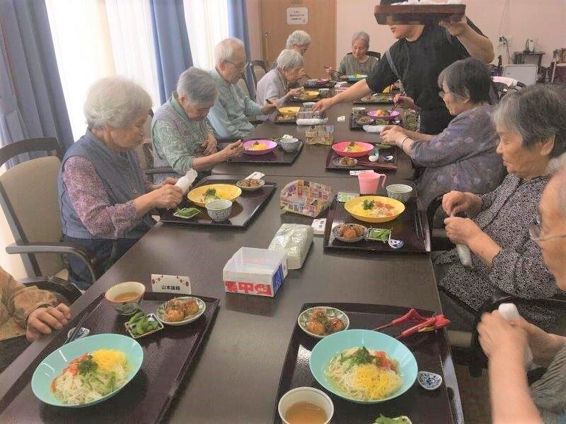 ご入居者がテーブルを囲み、冷たいそうめんを食べている様子