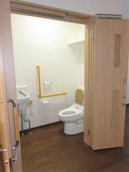 エル字型の手すりと緊急コールが取り付けられている施設内のトイレの様子