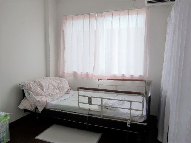 居室のベッドには手すりが付き、窓にはカーテンが付けられている。