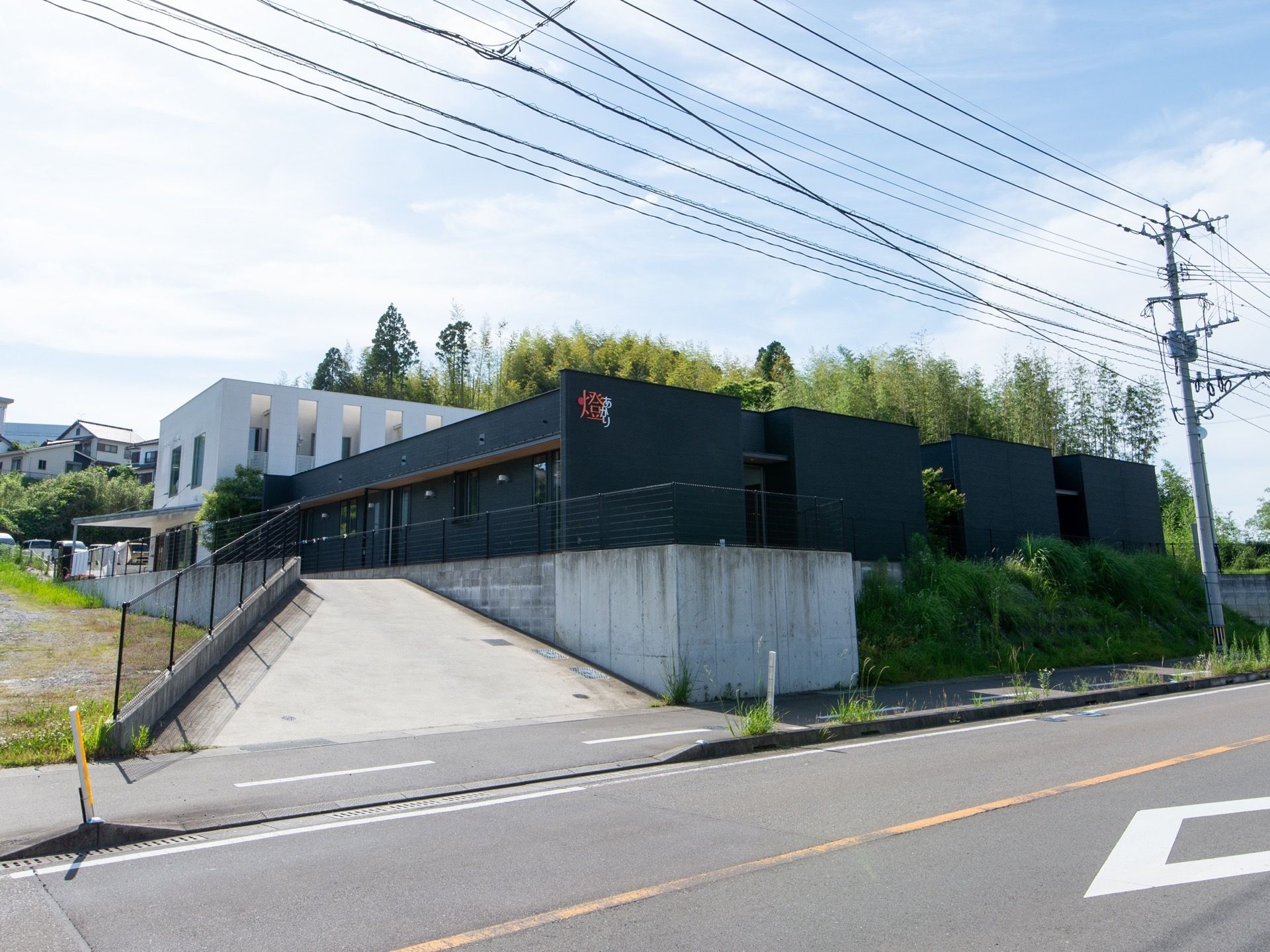 白と黒のツートンカラーが印象的な建物。入口横には奥に設置された駐車スペースへとつながるスロープが設けられている。