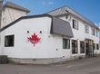 赤いメープルの歯のイラストの上にはCanadaと書かれ、グレーの屋根が付いた２階建ての建物。