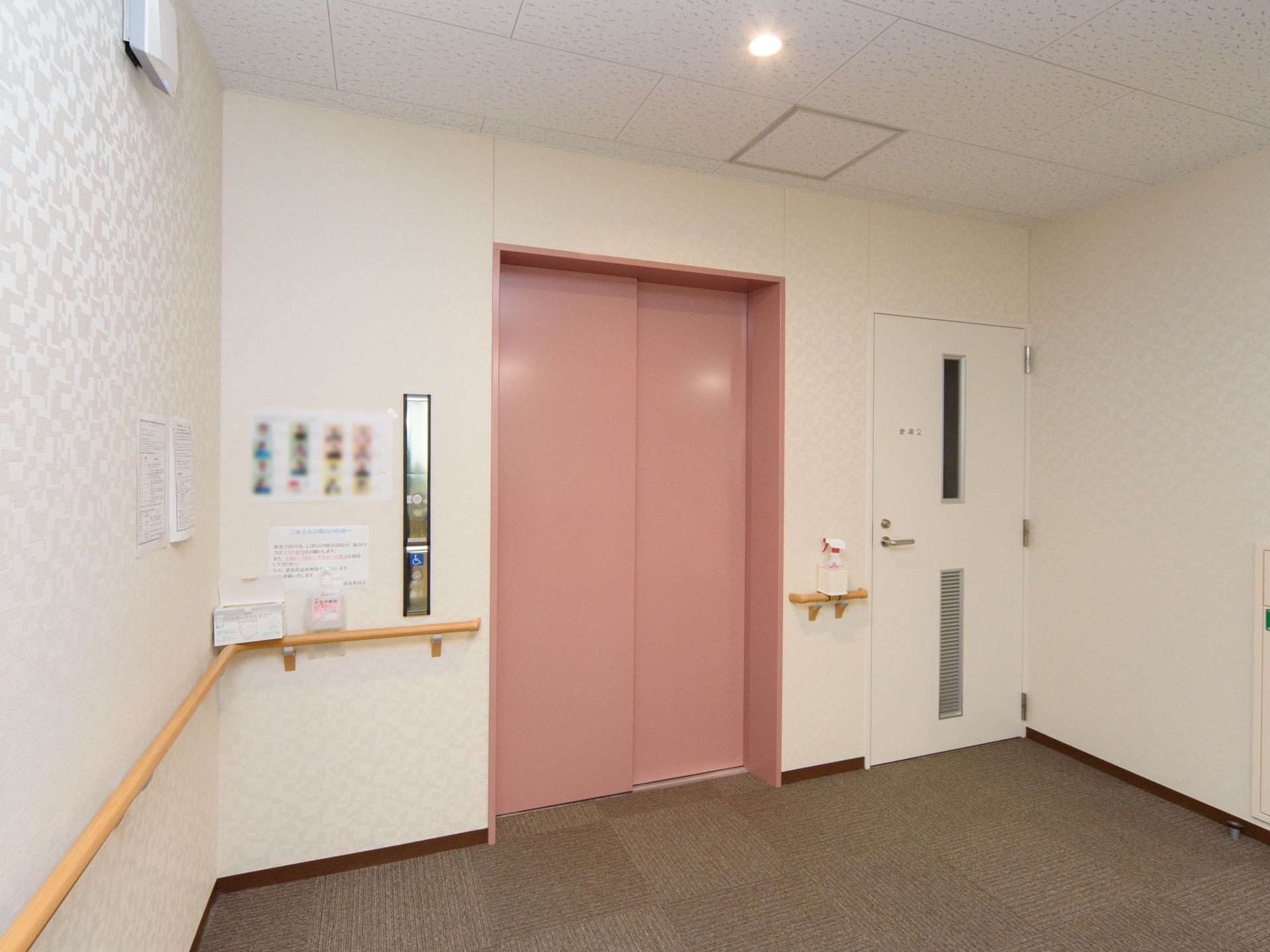 エレベーターのドアは明るいピンクに塗られている。ドアの際まで手すりが設置してあり、足腰の弱い方も乗り降りしやすい。